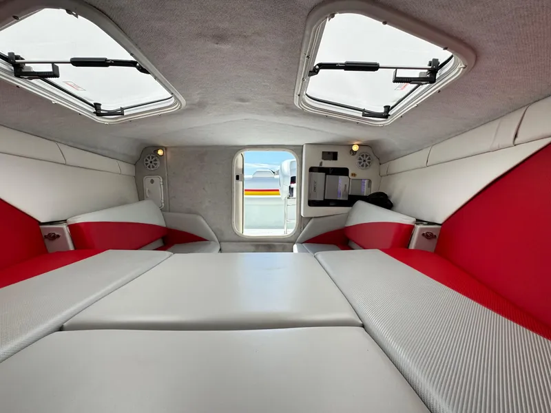 Slide: The Image of 2007 Baja 26 Outlaw cabin interior with red and white seating, skylights, and compact design. - 22