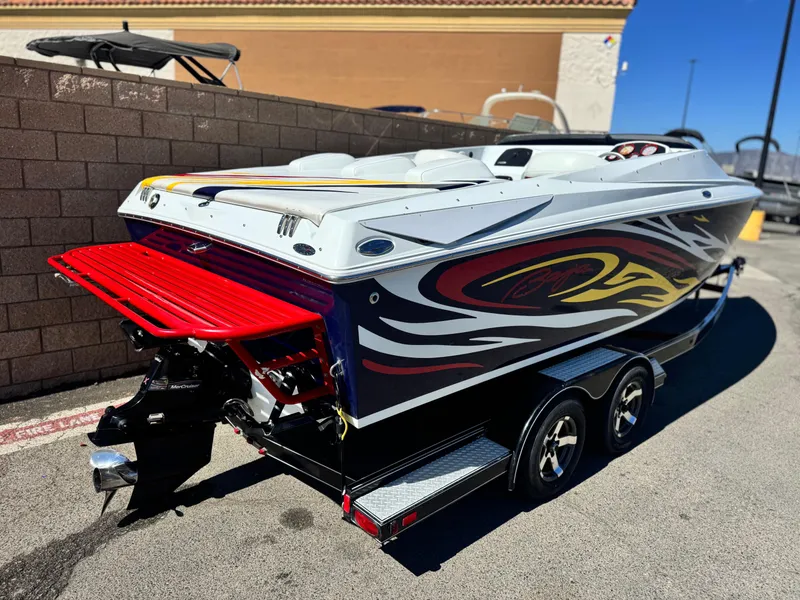Slide: The Image of 2007 Baja 26 Outlaw boat with vibrant graphics on a trailer, parked outdoors. - 5