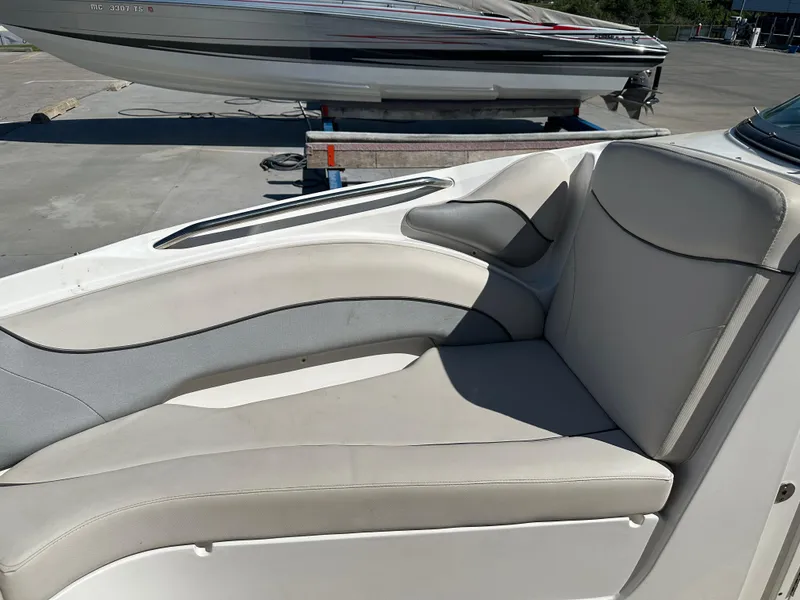Slide: The Image of 2014 Rinker Captiva 246 BR boat interior with beige seating, docked outdoors. - 16