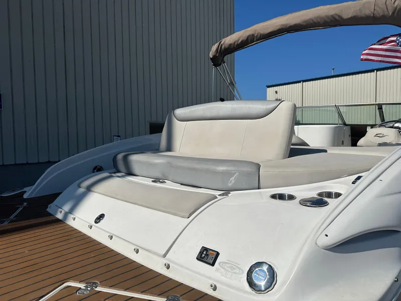 Slide: The Image of 2014 Rinker Captiva 246 BR boat with cushioned seating and cup holders, docked near a building. - 17