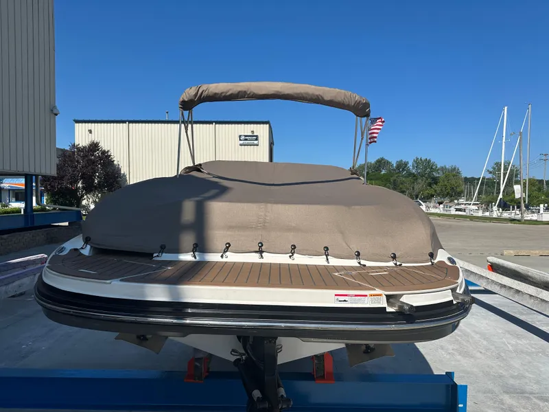 Slide: The Image of 2014 Rinker Captiva 246 BR boat with cover, docked at marina under clear blue sky. - 18