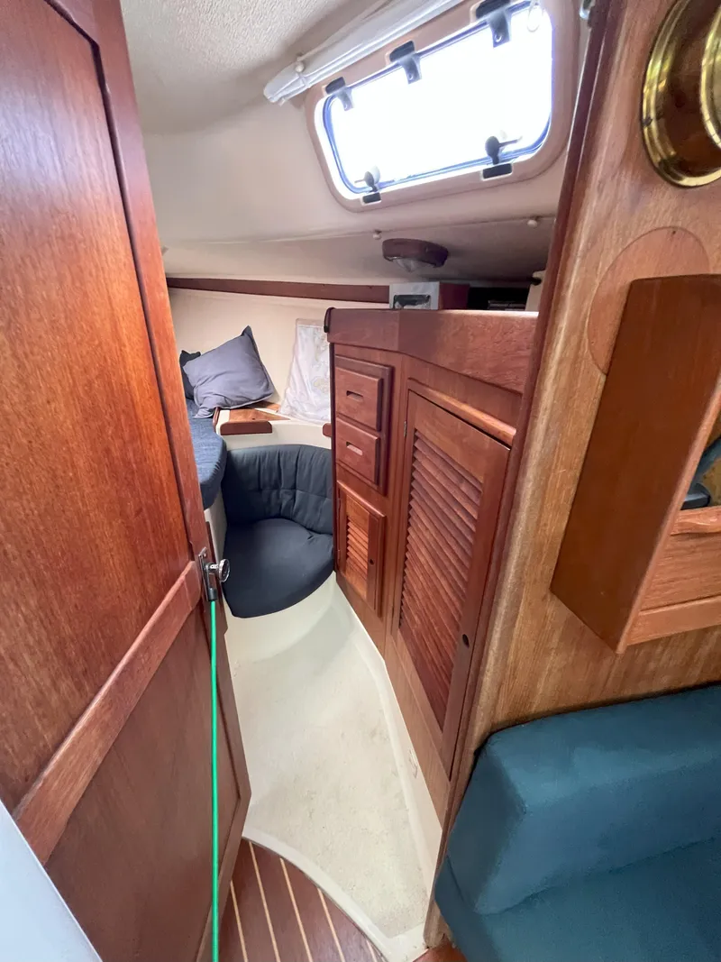 Slide: The Image of 1988 Tartan 31 sailboat interior with wooden cabinetry and cozy sleeping area. - 14