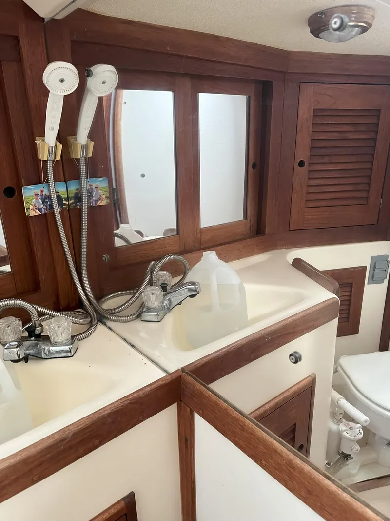 Slide: The Image of 1988 Tartan 31 yacht bathroom with wooden cabinets, dual shower heads, and a white sink. - 17