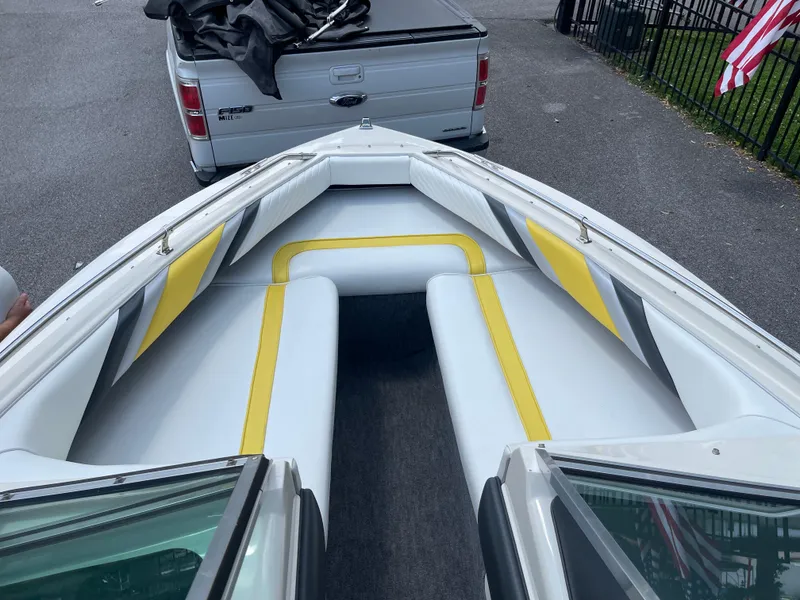 Slide: The Image of 1990 Sea Ray 180 Bow Rider with yellow and gray interior, parked near a Ford F-150. - 5