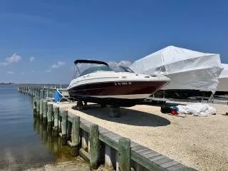 Slide: The Image of 2006 Sea Ray 220 Sundeck boat docked by a serene waterfront. - 1