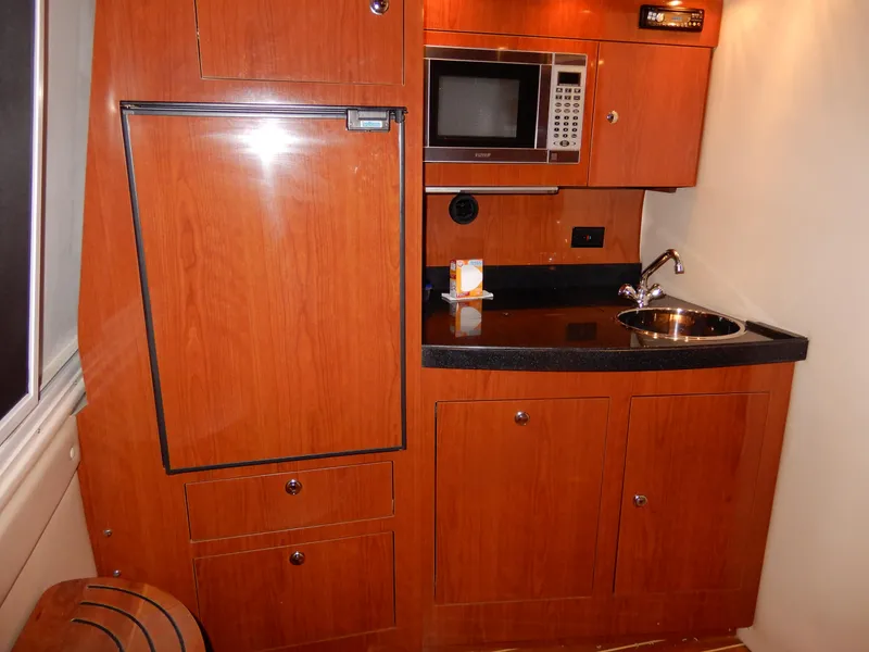 Slide: The Image of 2006 Regal Commodore 3760 IO yacht kitchenette with wood cabinetry, microwave, and sink. - 33