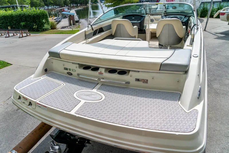 Slide: The Image of 2009 Sea Ray 210 Select boat with spacious seating and sleek design at a marina. - 9