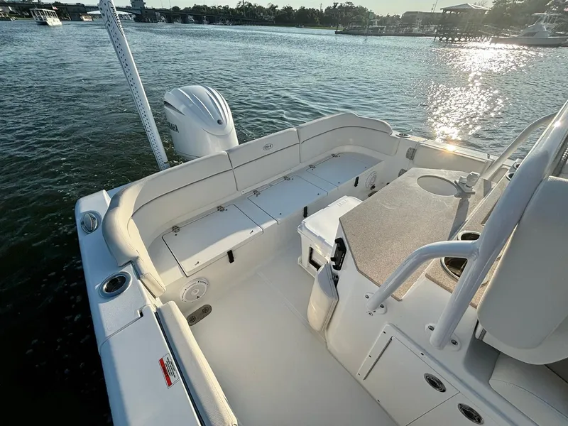 Slide: The Image of 2023 Sea Hunt Escape 25 boat interior with seating and storage, docked on a sunny day. - 11