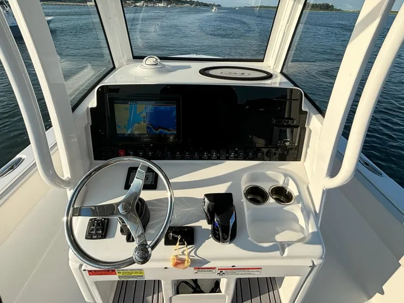 Slide: The Image of 2023 Sea Hunt Escape 25 boat dashboard with steering wheel, navigation screen, and cup holders. - 12