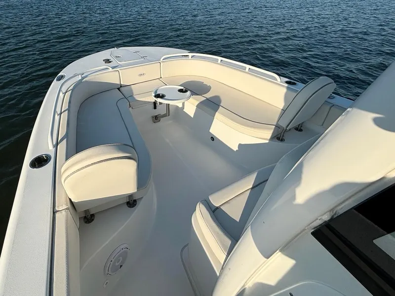 Slide: The Image of 2023 Sea Hunt Escape 25 boat interior with white seating and table on calm water. - 9