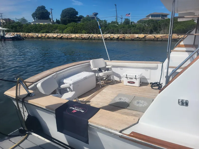 Slide: The Image of 1989 Ocean Yachts 48 boat deck with seating and coolers, docked by a scenic shoreline. - 10