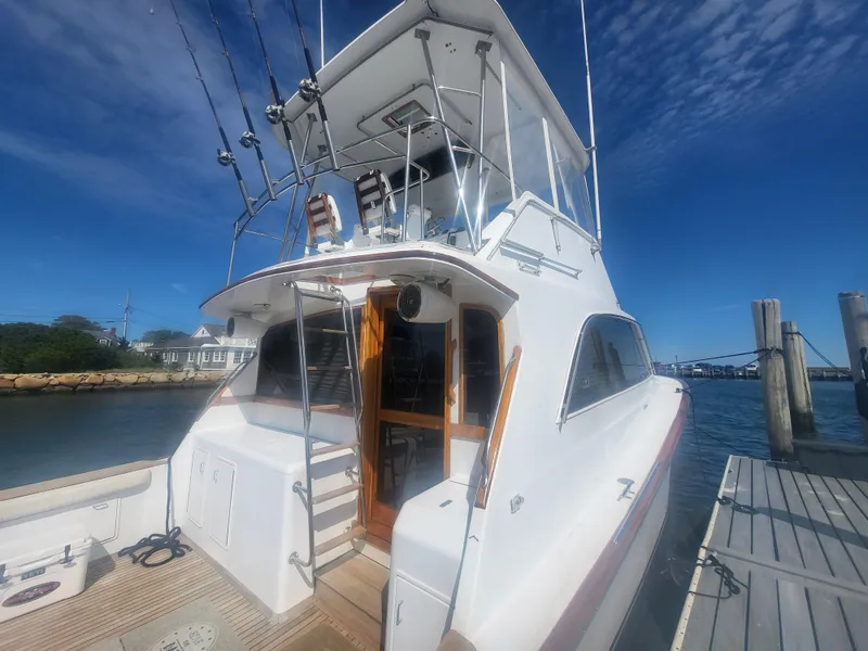 Slide: The Image of 1989 Ocean Yachts 48 docked, featuring flybridge and fishing rods under clear blue sky. - 3