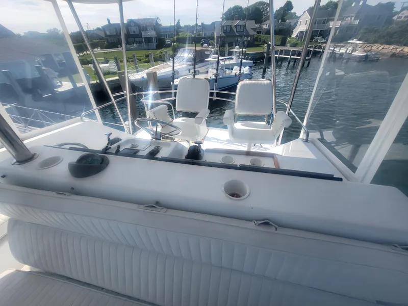Slide: The Image of 1989 Ocean Yachts 48 cockpit with white seating, docked near waterfront homes. - 44