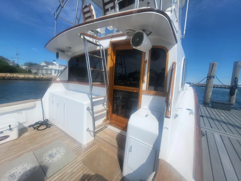 Slide: The Image of 1989 Ocean Yachts 48 docked, showcasing rear deck and cabin entrance under clear blue sky. - 6