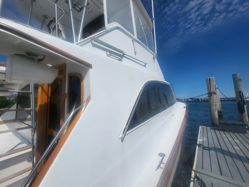 Slide: The Image of 1989 Ocean Yachts 48 docked, showcasing sleek design and wooden accents under a clear blue sky. - 7