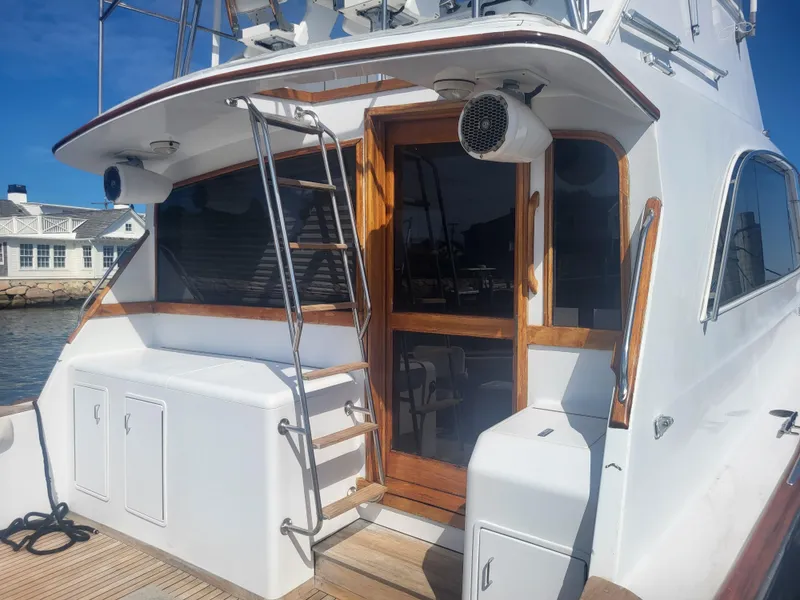 Slide: The Image of 1989 Ocean Yachts 48 boat with wooden accents and ladder, docked by a waterfront house. - 8