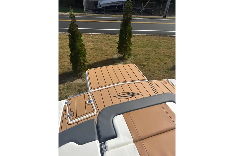 Slide: The Image of 2026 Chaparral 23 SSi boat deck with tan and white upholstery, near roadside greenery. - 21