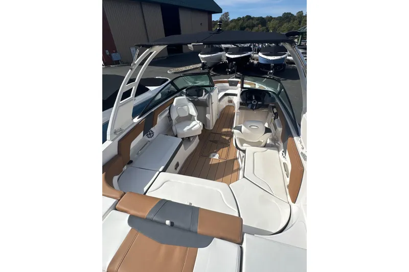 Slide: The Image of 2026 Chaparral 23 SSi boat interior with seating and steering wheel, docked outdoors. - 23