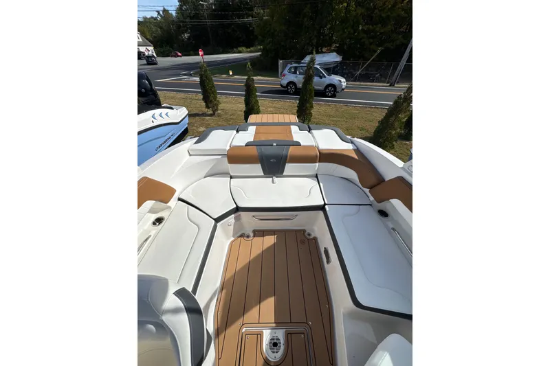 Slide: The Image of 2026 Chaparral 23 SSi boat interior with tan and white seating, docked near a road. - 25