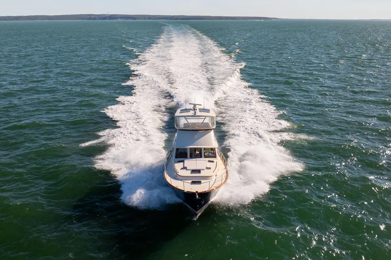 Slide: The Image of 2014 Hinckley Talaria 48 Flybridge cruising on open water, leaving a wake. - 2