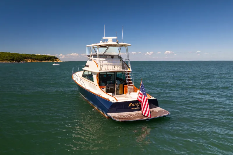 Slide: The Image of 2014 Hinckley Talaria 48 Flybridge yacht on open water, American flag displayed. - 4