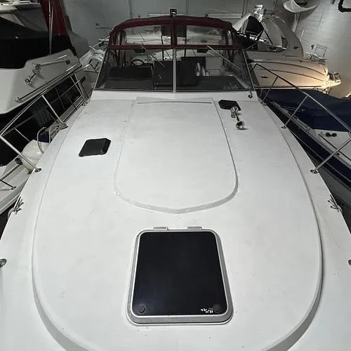 Slide: The Image of 1990 Carver 3257 Montego boat with white deck and red canopy in storage. - 11