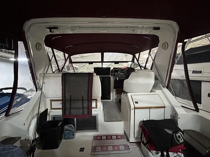 Slide: The Image of 1990 Carver 3257 Montego boat interior with maroon canopy and white seating. - 14