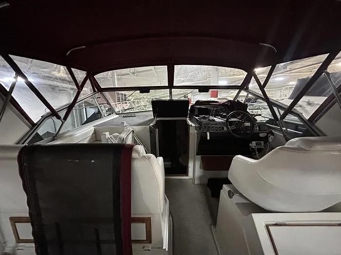 Slide: The Image of Interior view of a 1990 Carver 3257 MONTEGO boat with white seating and steering area. - 15