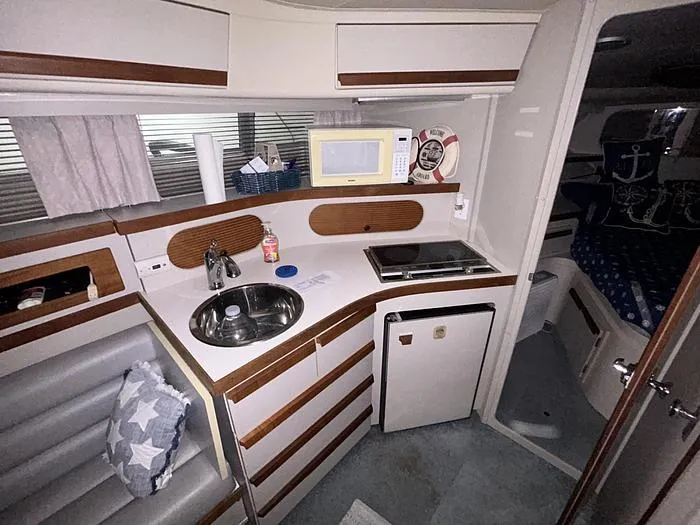 Slide: The Image of 1990 Carver 3257 MONTEGO boat interior with kitchenette, featuring sink, stove, and microwave. - 23