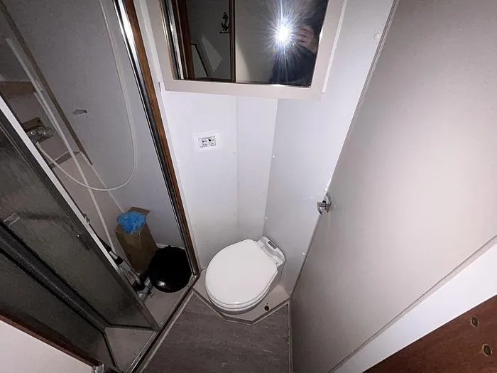 Slide: The Image of Compact bathroom in a 1990 Carver 3257 MONTEGO boat, featuring a toilet and shower. - 32