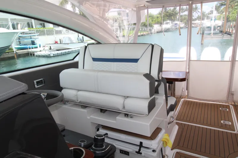 Slide: The Image of 2021 Tiara Yachts 38LX interior with helm seat, wooden flooring, and marina view. - 18