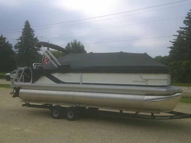 Slide: The Image of 2026 Godfrey 2286 Sweetwater Cruise Special Edition pontoon boat on trailer, covered and parked. - 18