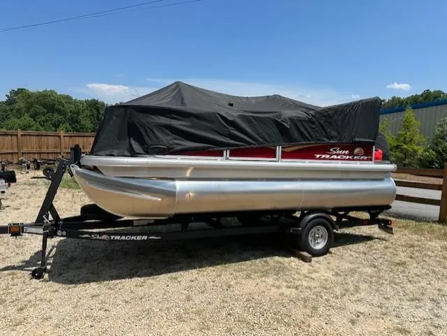 Slide: The Image of 2024 Sun Tracker Bass Buggy 16 XL Select pontoon boat on trailer, covered, outdoors. - 18