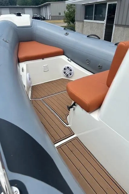 Slide: The Image of 2022 Brig Navigator 485 boat interior with orange seating and wood-style flooring. - 2