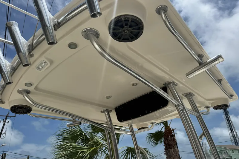 Slide: The Image of 2016 Ranger 2510 Bay Ranger T-top with rod holders and speakers, under a clear blue sky. - 7