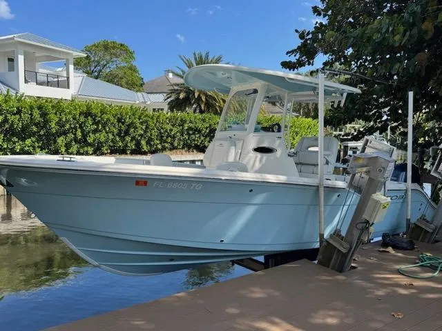 The Image of 2022 Cobia 240 Center Console boat on lift, dockside, under cloudy sky. - 0