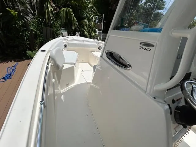 Slide: The Image of 2022 Cobia 240 Center Console boat docked by a wooden deck, surrounded by lush greenery. - 10