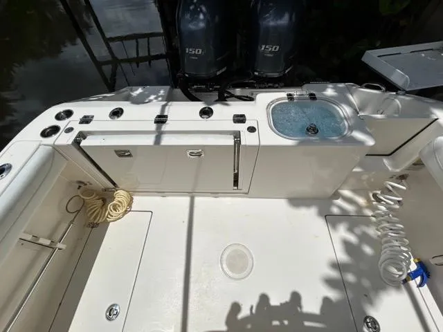 Slide: The Image of 2022 Cobia 240 Center Console boat docked by a wooden deck, surrounded by lush greenery. - 21