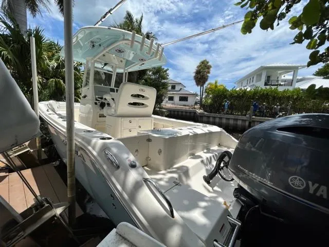 Slide: The Image of 2022 Cobia 240 Center Console boat with speakers and rod holders under blue canopy. - 24