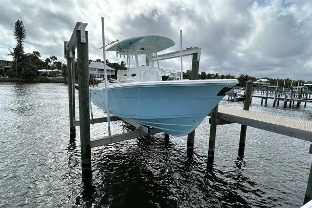Slide: The Image of 2022 Cobia 240 Center Console boat docked on a lift by a pier. - 28
