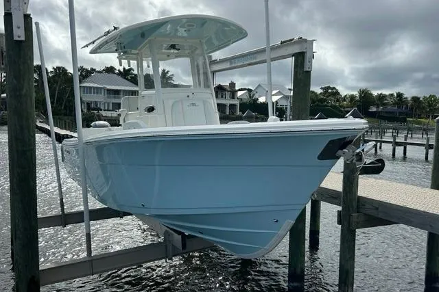 Slide: The Image of 2022 Cobia 240 Center Console boat on lift, dockside, with overcast sky. - 31