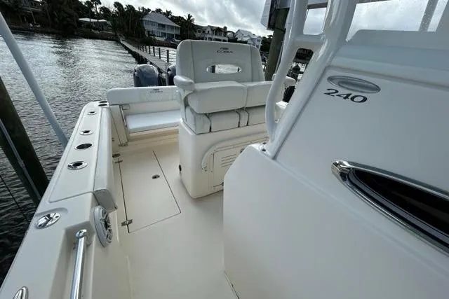 Slide: The Image of 2022 Cobia 240 Center Console boat interior, featuring seating and console details by the water. - 44