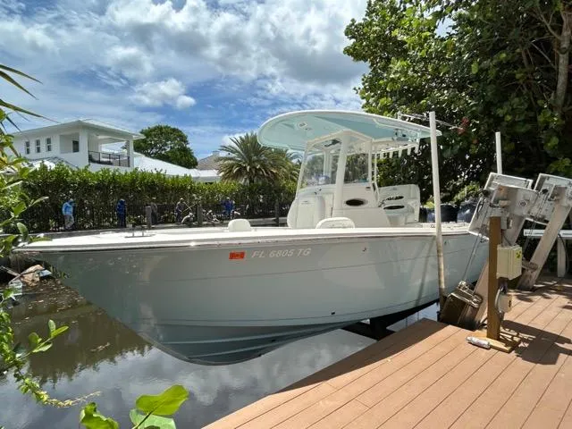 Slide: The Image of 2022 Cobia 240 Center Console boat docked by a wooden pier, surrounded by lush greenery. - 9