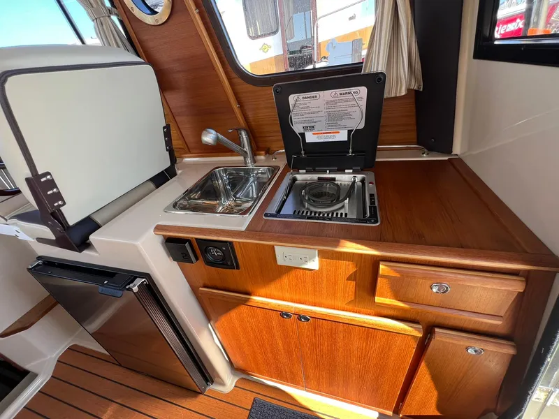 Slide: The Image of 2018 Ranger Tugs R23 interior kitchen with sink, stove, and wooden cabinetry. - 14