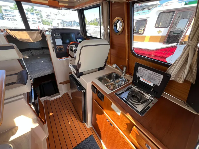 Slide: The Image of 2018 Ranger Tugs R23 interior with kitchenette, steering console, and seating area. - 15