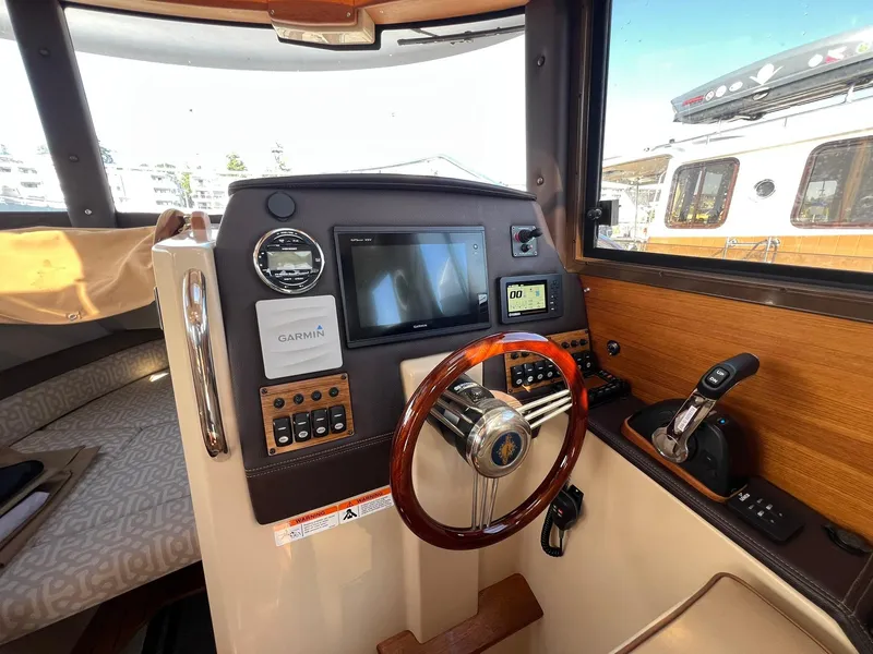 Slide: The Image of 2018 Ranger Tugs R23 helm with Garmin navigation, wooden steering wheel, and control panel. - 16