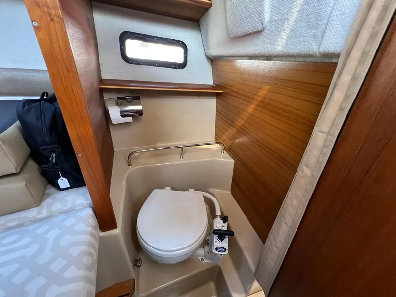 Slide: The Image of 2018 Ranger Tugs R23 boat interior with compact marine toilet and wooden paneling. - 18