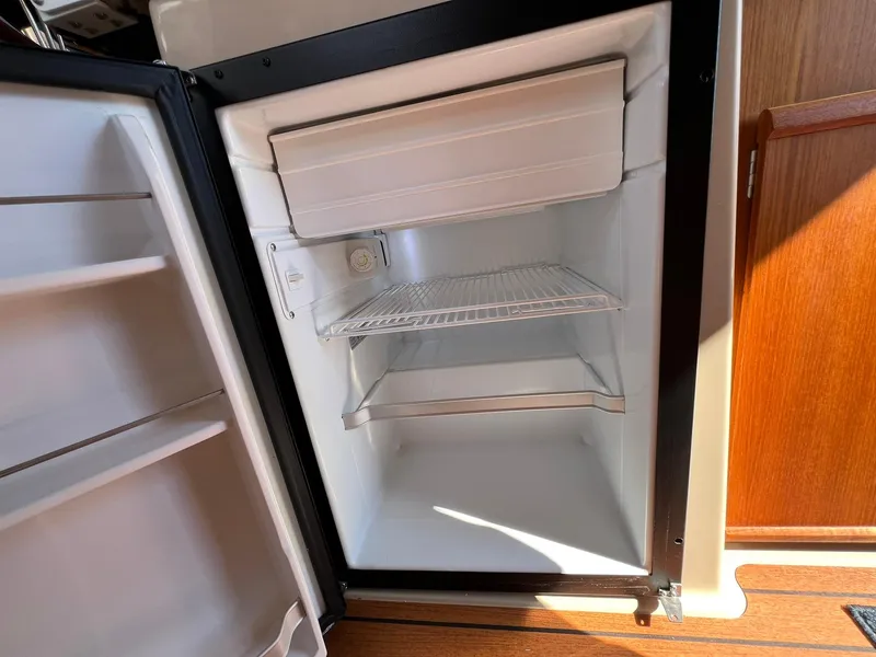 Slide: The Image of Open refrigerator inside 2018 Ranger Tugs R23 boat, featuring shelves and freezer compartment. - 19