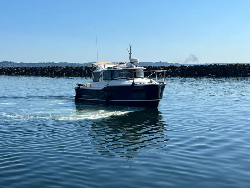 Slide: The Image of 2018 Ranger Tugs R23 boat cruising on calm water near rocky shoreline. - 3