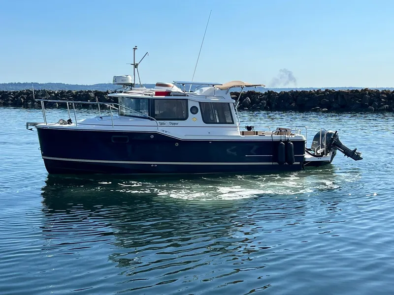Slide: The Image of 2018 Ranger Tugs R23 boat cruising on calm water near rocky shoreline. - 5